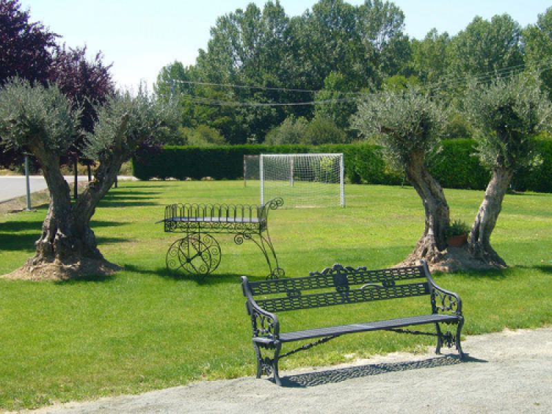 Banco de hierro en jardín con árboles