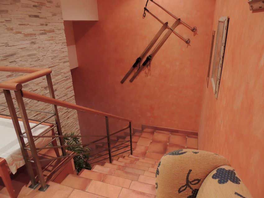 Recibidor con escaleras decorado con un arado en la pared